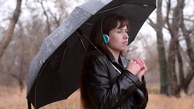 The woman got wet in the rain. The woman listens to music in earphones.