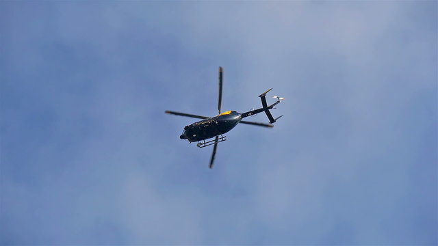 A black helicopter going around the city in London during the day time