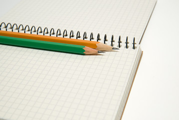 Opened notebook and pencils on over white