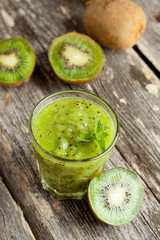 glass of kiwi juice with fresh fruits on wooden table