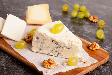 Blue cheese with grapes and nuts on wooden board