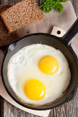 Scrambled eggs in an iron pan on the rustic wooden table