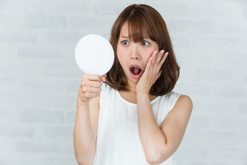 鏡を見て驚く女性