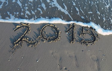 inscription year 2015 in the sand of the sea with waves