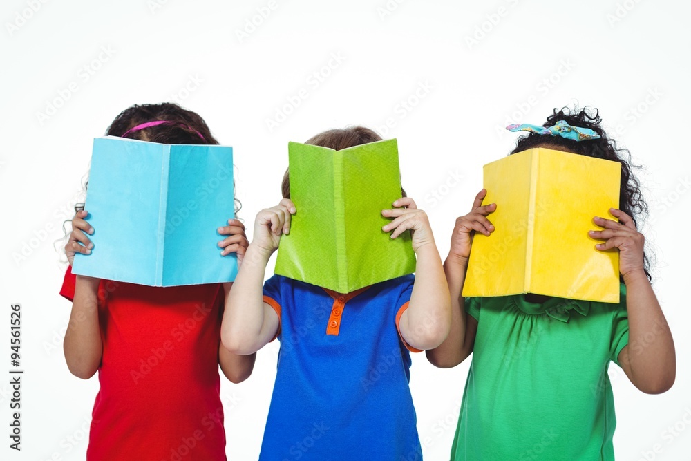 Wall mural Three kids standing with books in front of their faces