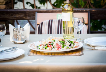 Caesar salad with chicken served with white wine at the terrace