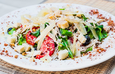 Fresh salad with parmesan cheese and croutons, chicken and tomat