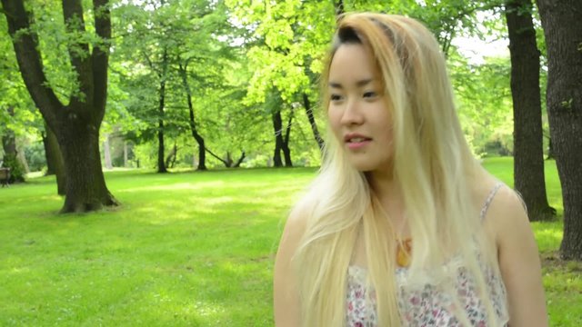 young asian attractive smiles woman walks in the park - emotions - steadicam