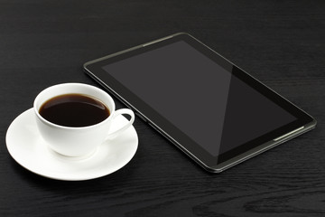 Fototapeta na wymiar tablet and a Cup of strong black coffee on wooden black background