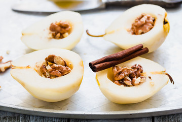 cooking process pear with walnuts, cinnamon sticks on an iron pl