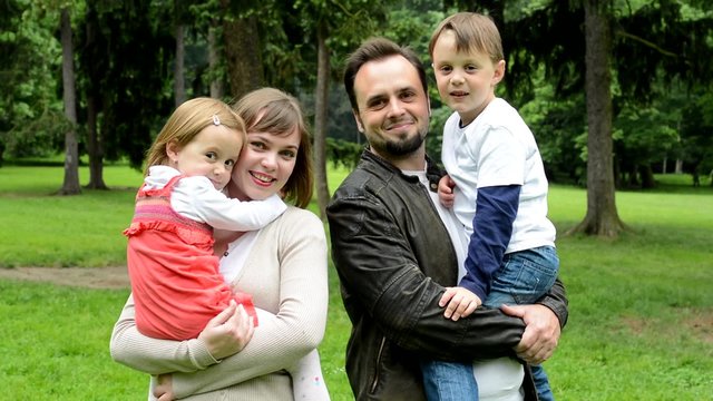 family (middle couple in love, cute girl and small boy) smile to camera in the park