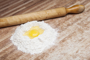 Fototapeta na wymiar Broken egg on flour, means for making bread
