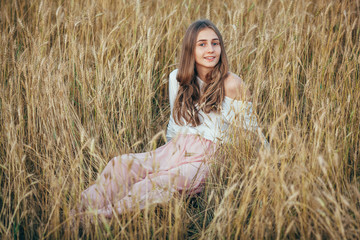 Young woman wearing dress sitting in field with wheat