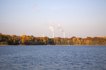 Smokestacks behind the lake and forest