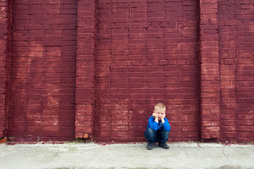 Fototapeta na wymiar Depressed child near brick wall