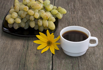 plate with grapes, a cup of coffee and a yellow flower, a still