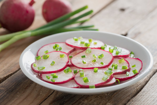 Spring salad with radish and green onions on wood table.