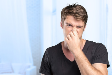 Young Man holding his nose against a bad smell - obrazy, fototapety, plakaty