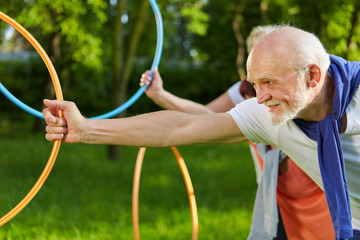 Senioren machen Sport mit Reifen im Garten