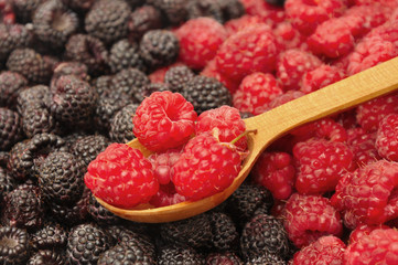 Blackberry and raspberry with wooden spoonful of berries in the middle