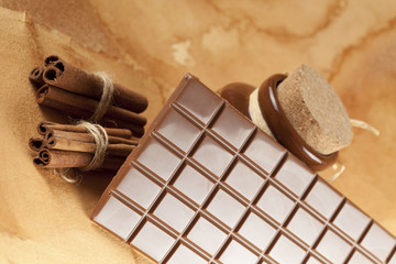 Homemade candy - chocolate, cocoa and cinnamon sticks on paper b