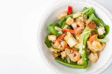 Caesar salad with shrimps on the white background top view