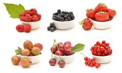 Collection of berries in white bowls: raspberry, blackberry, strawberry, gooseberry, cherry, redcurrant