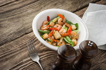 Prawns Caesar salad with fork on the wooden table horizontal