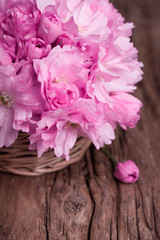 Pink flowers in a straw basket on a vintage surface