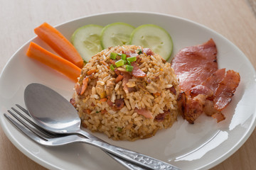 Fried rice with bacon and vegetables on wood table.