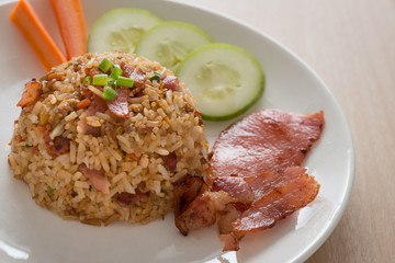Fried rice with bacon and vegetables on wood table.