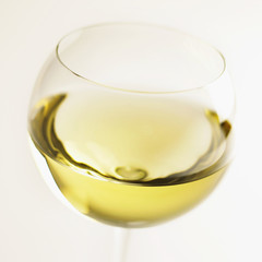 Glass of red wine and an opened bottle of red wine out of focus behind.