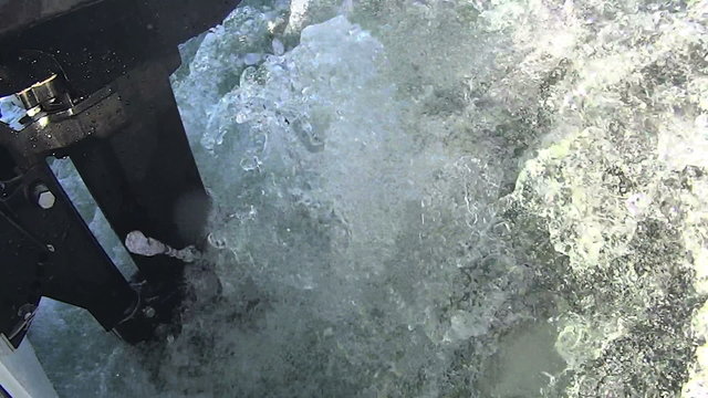Outboard motor on boat running with wake and waves.