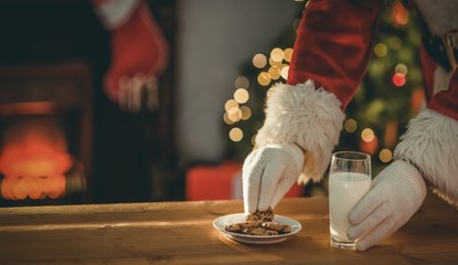 Santa claus picking cookie and glass of milk - Powered by Adobe