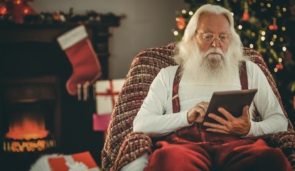 Santa claus using tablet on the armchair