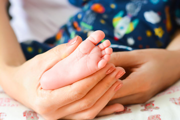 Obraz na płótnie Canvas Mother holding baby feet in her palms