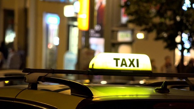 sign on the car - taxi - night - urban street in the city with cars and people