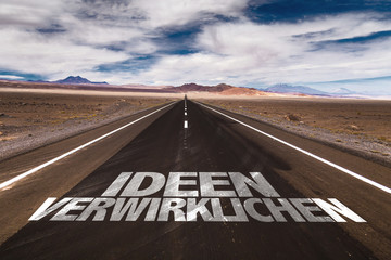 Realize Ideas (in German) written on desert road