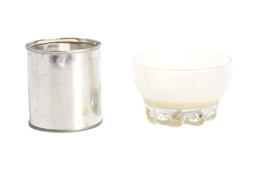 Condensed milk with sugar in glass bowl and tin can