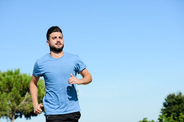 handsome young man during fitness exercises and running outdoor in summer