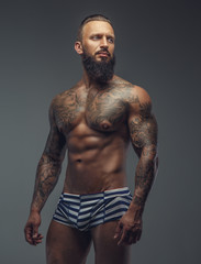 Fototapeta premium Tattooed muscular man with beard in stripes panties.