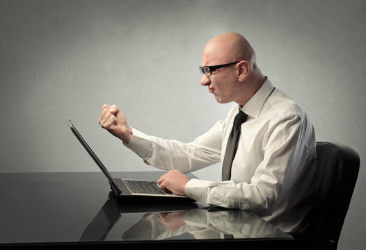Angry businessman in front of a laptop