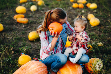 Fototapeta premium Mother and daughter sitting on pumpkins