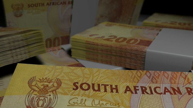 An extreme closeup pan of variously placed bundled wads of south african rand banknotes on a dark background