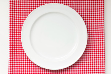 white dish or plate on red classic checkered tablecloth texture on white table with copy space for advertise food product and other
