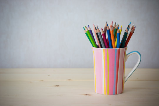 Still life color pencils in colorful cup on wooden table - vintage effect style picture
