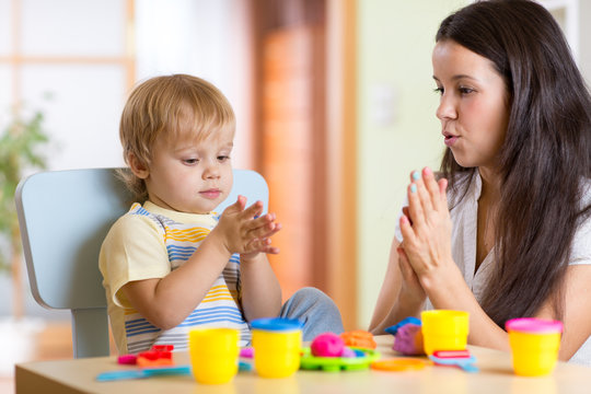 child boy and woman playing colorful clay toy at nursery or kindergarten