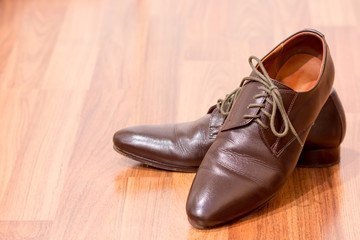 A pair of men's brown leather shoes on wooden floor