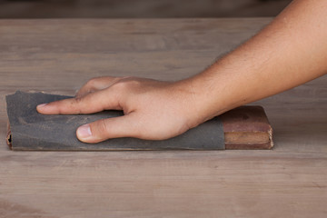 Handyman working with sandpaper on a wooden table