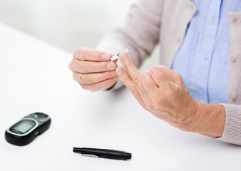 Obraz na płótnie Canvas senior woman with glucometer checking blood sugar
